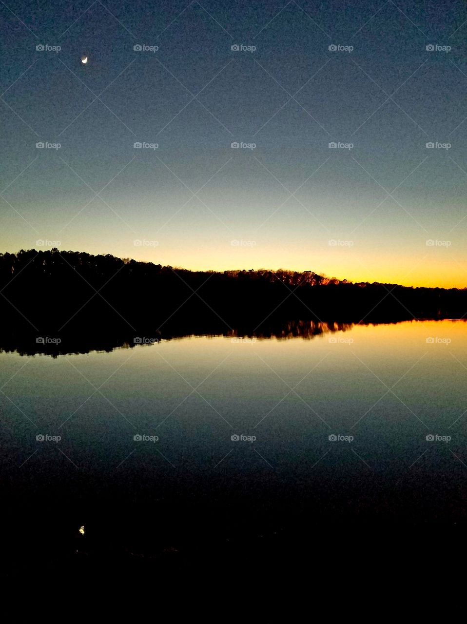 crescent moon reflected over lake.