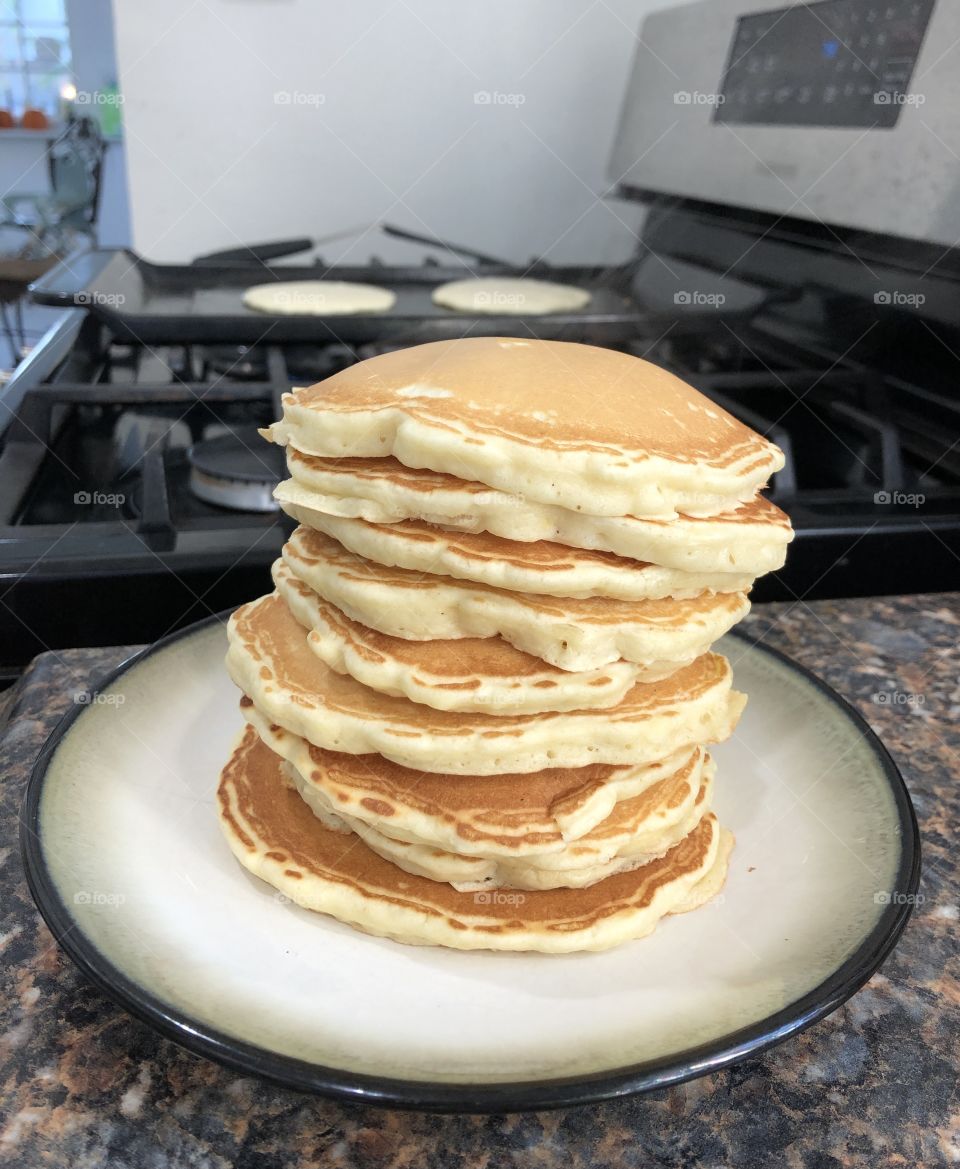 Stack of pancakes on counter with griddle in the background 