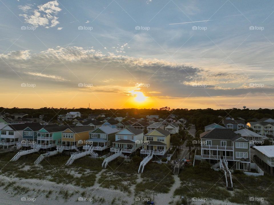 As the sun sets on a beautiful summer day at the beach, the vibrant colors of the vacation homes provide a beautiful pop of color against the white sand
