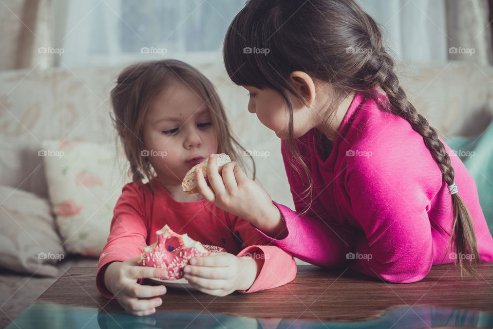 Little sisters eating donuts 