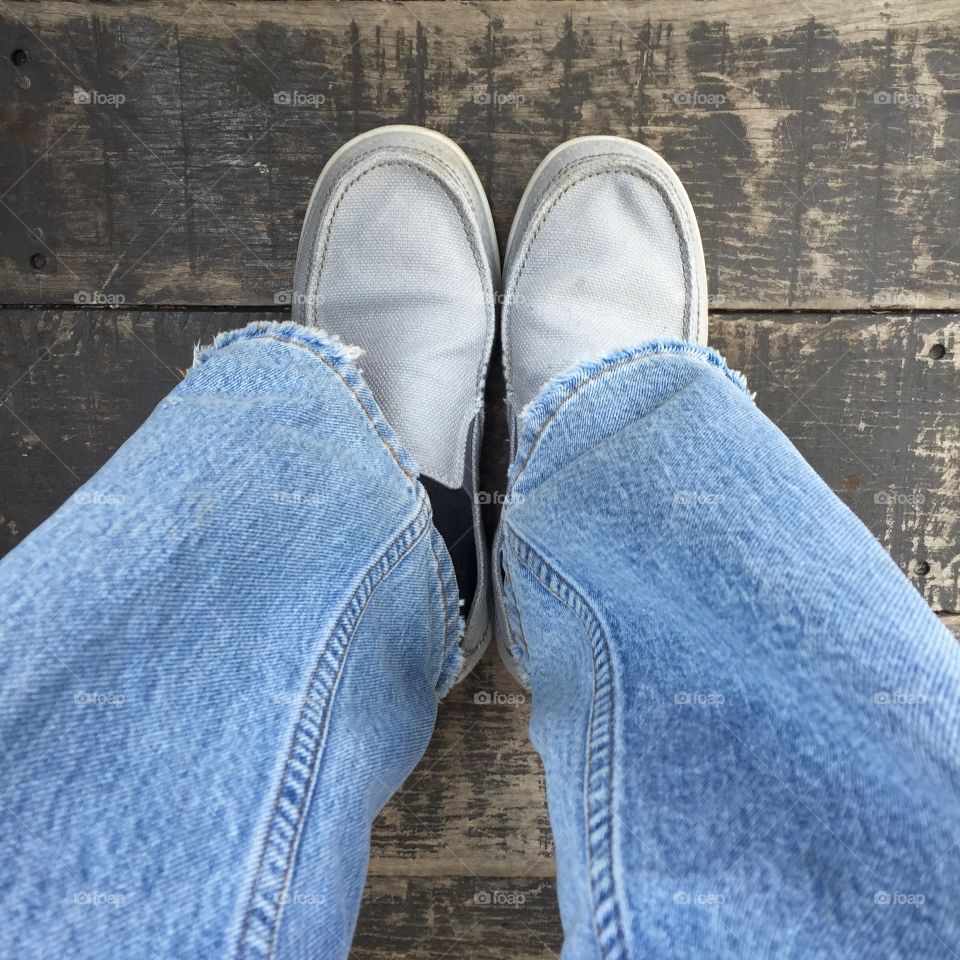 Low section of a man wearing gray shoes and blue jeans