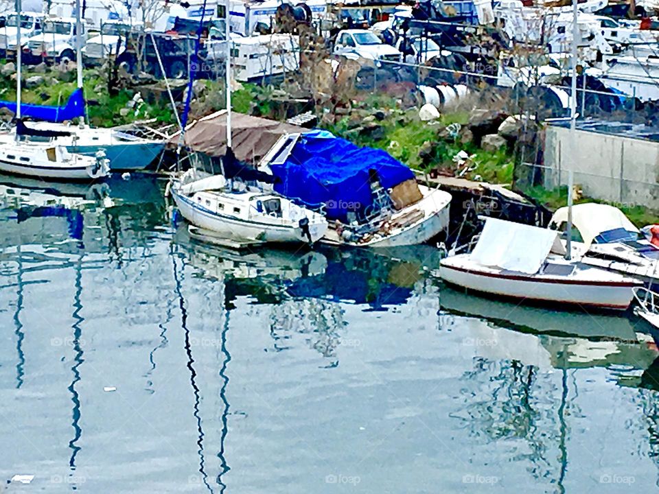 Sailboats at Newtown Creek in Long Island City, Queens, NY at high tide next to the shore seen from the top of the Pulaski Bridge on a late afternoon in 2021 just as twilight time approaches. Hypnotic Productions