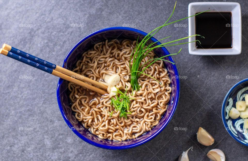 Noodles with fresh garlic and chives and a side of soy sauce on a slate background 