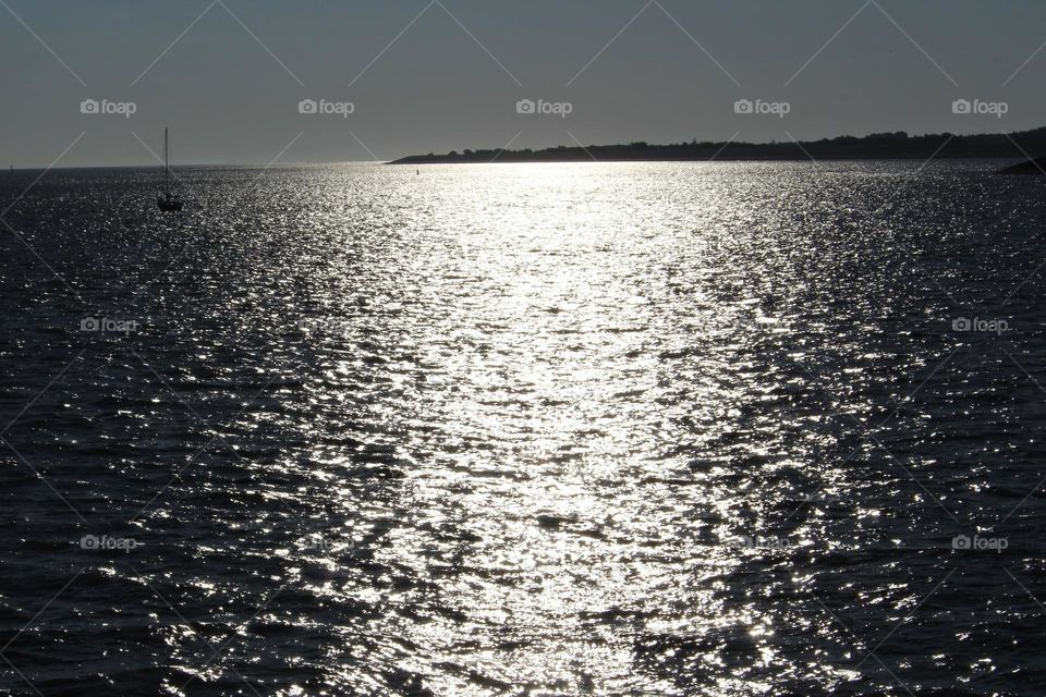 in the early morning sun, a fishing ship sails from Waddensea to the Northsea. The sun is already shinning beautiful over the water.