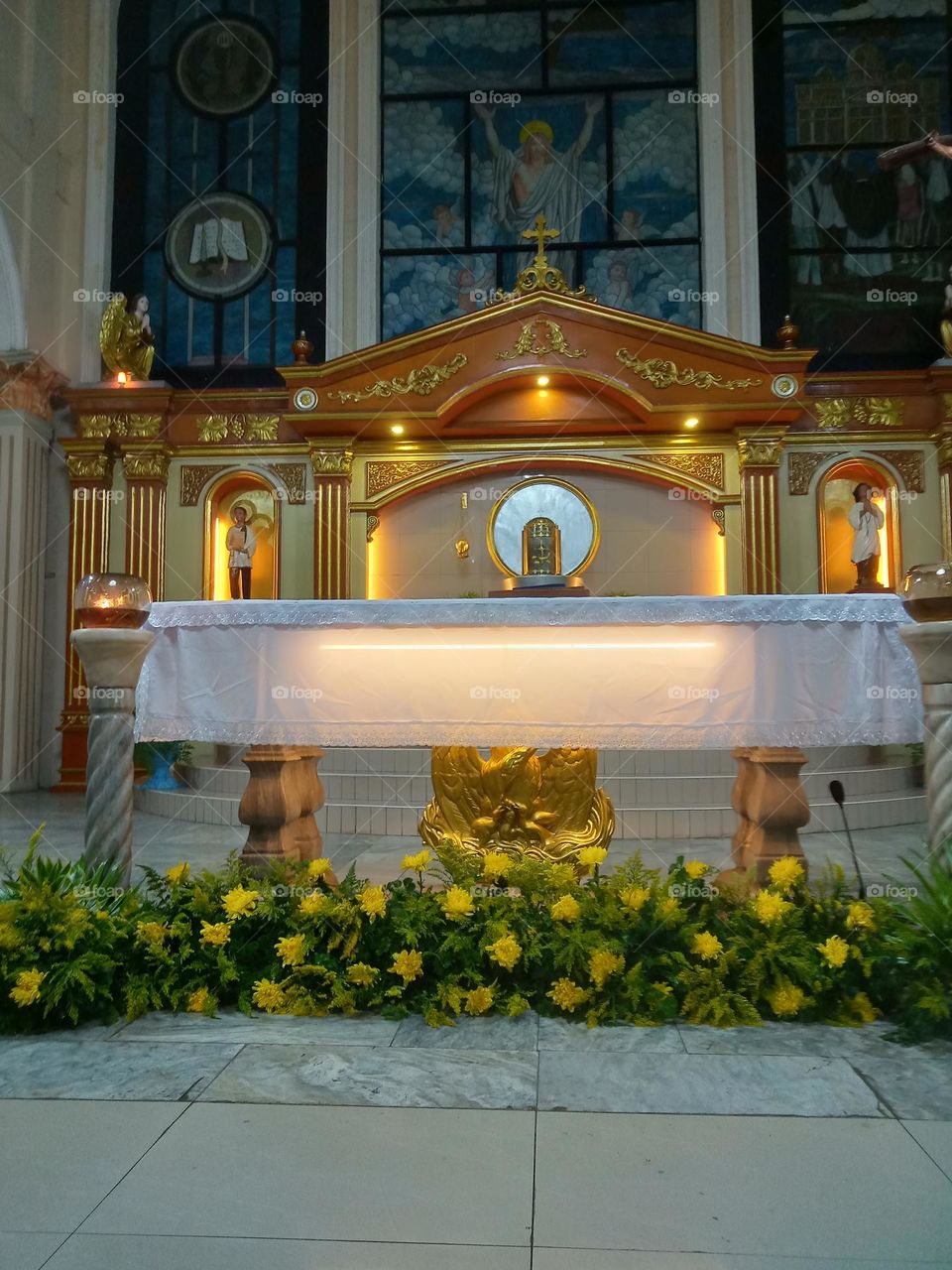FLOWERS, CANDLES, LIGHTS ON, AND TABLE IS BEING PREPARED FOR THE  HOLY CATHOLIC MASS TO BE OFFERED,