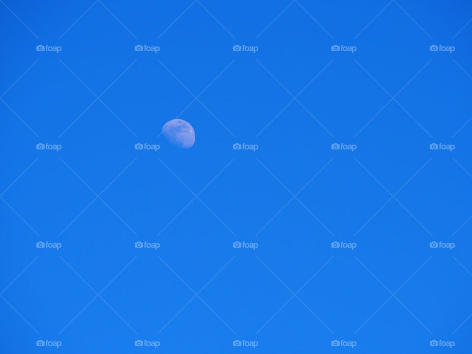 View of half moon in blue sky