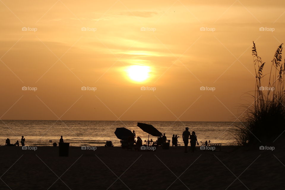 On the beach at sunset , silhouettes of people 