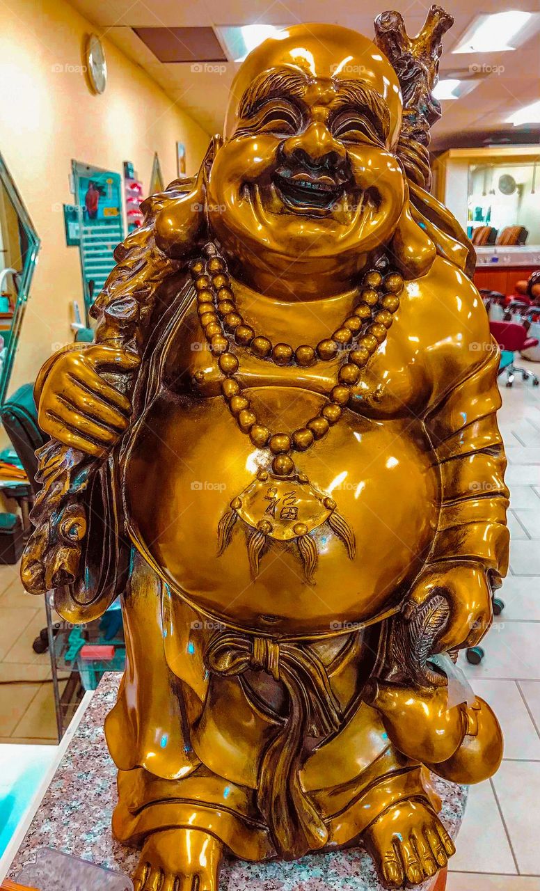 A large bronze statue of Laughing Buddha. This iconic figure symbolizes unlimited joy, good fortune and prosperity.