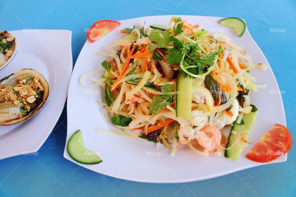 seafood salad on white dish on blue background.