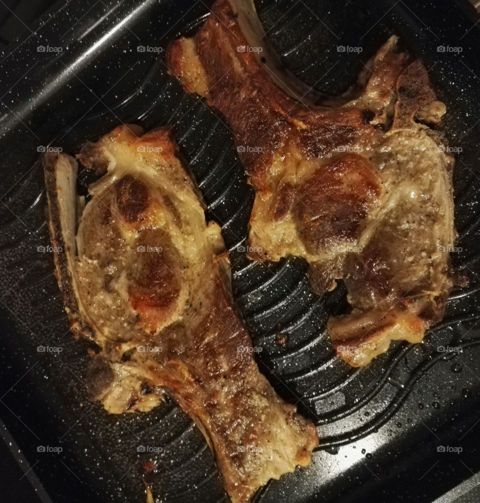 two pork chops in frying pan closeup