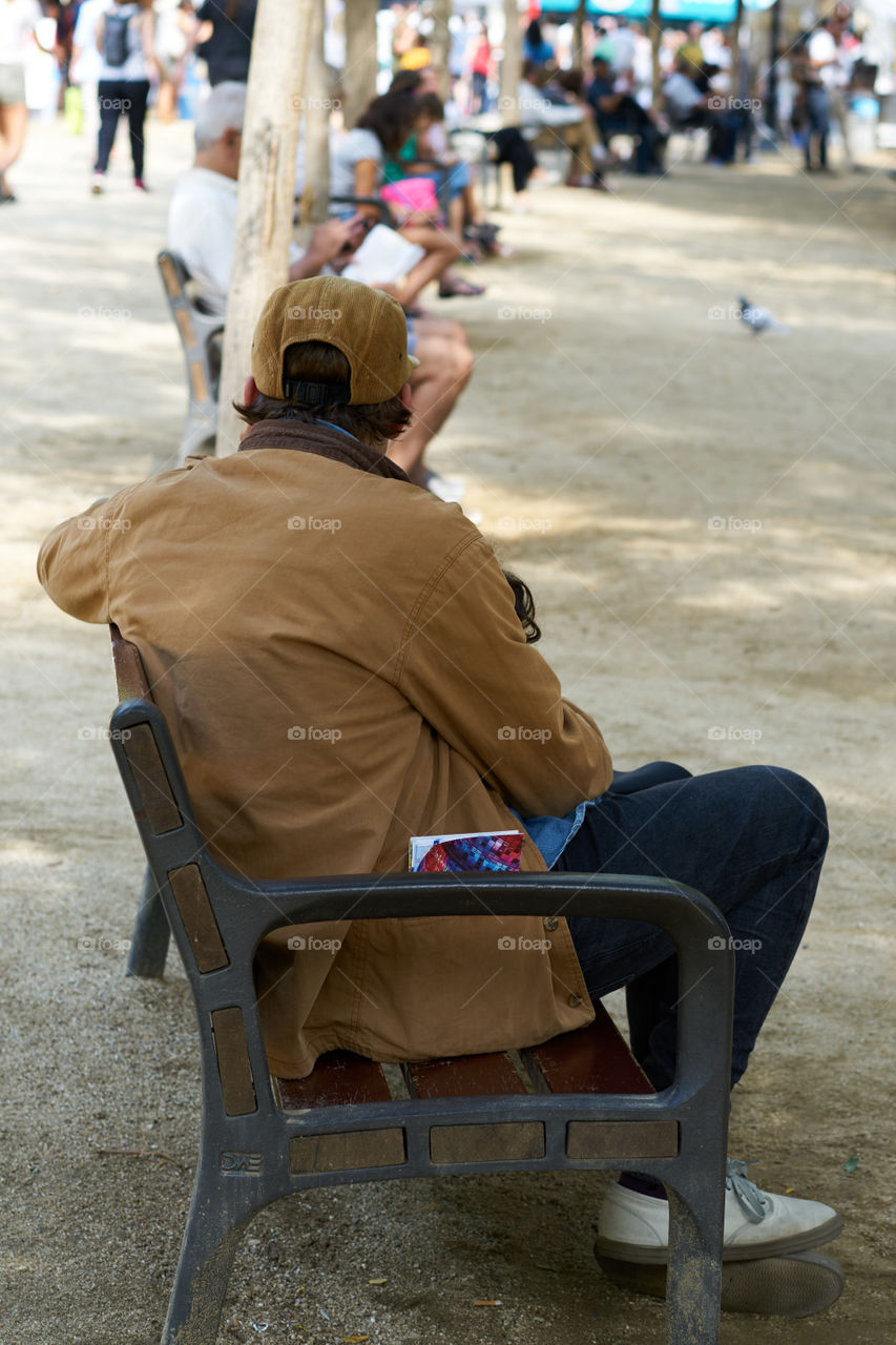 Elderly man sitting in a street bench