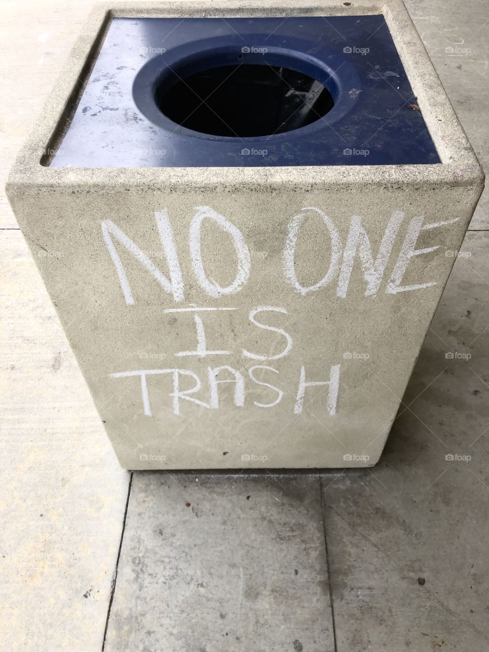 No one is trash captioned on cement garbage receptacle in white chalk handwriting 