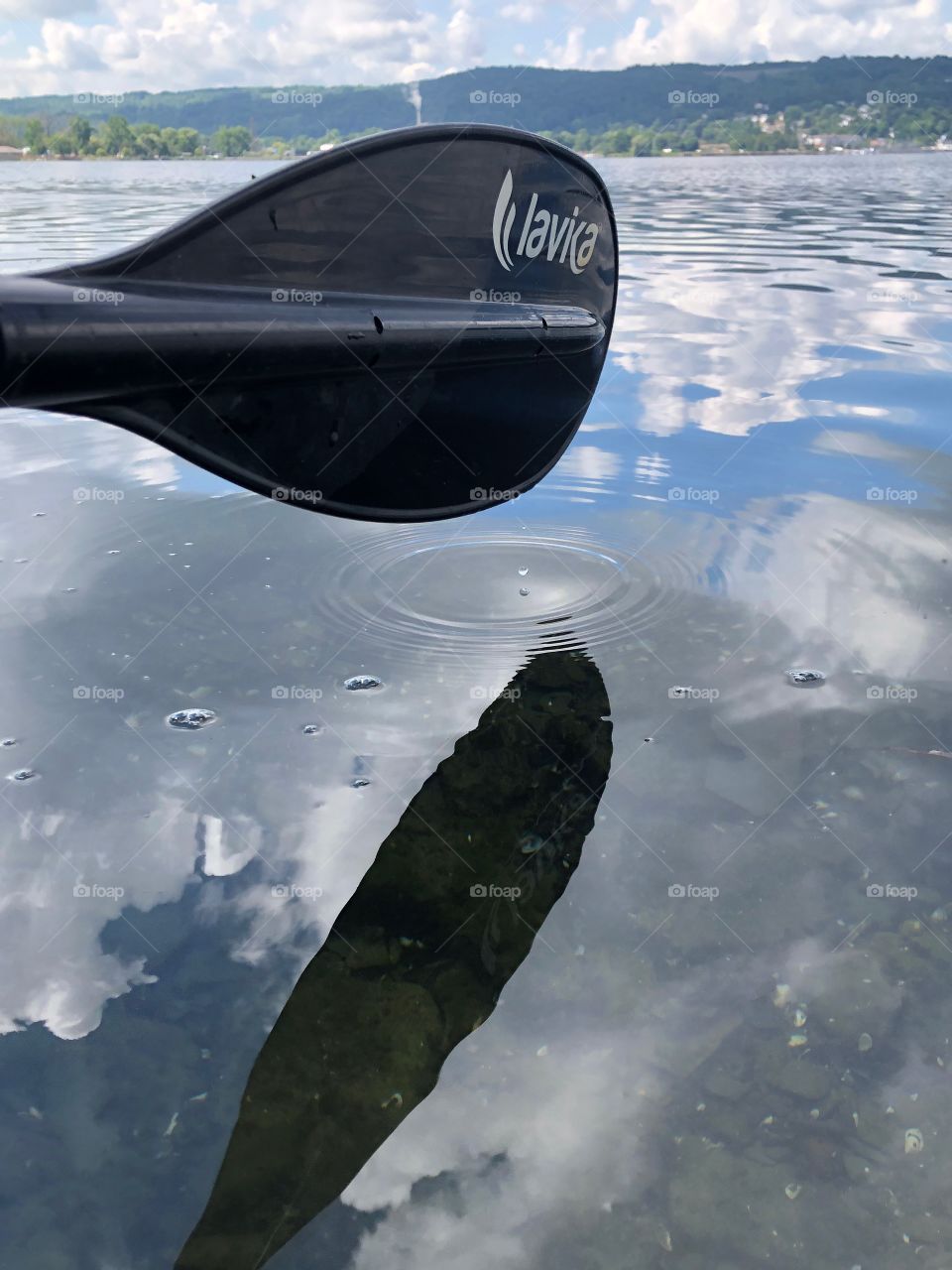 A paddle with a beautiful reflection with ripples in the water. Well placed over the water with beautiful sky and clouds. 