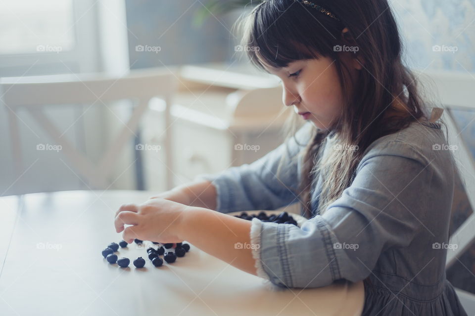 Little girl with blueberries at morning 