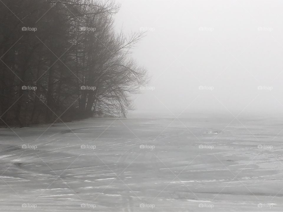 Icy lake on a frigid winter day in Massachusetts. The fog rolling in makes it eerily quiet.