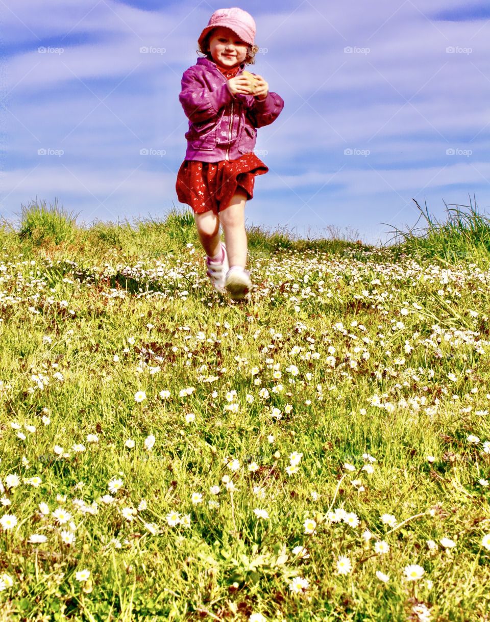 Girl running through field of flowers in spring 