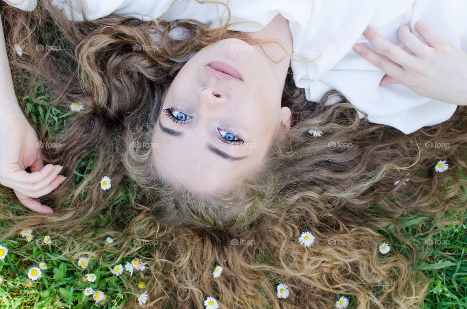 Portrait of a Beautiful Young Girl on Background of Daisies