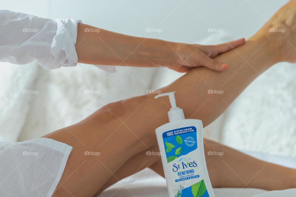 Woman applying Body Lotion on her legs 