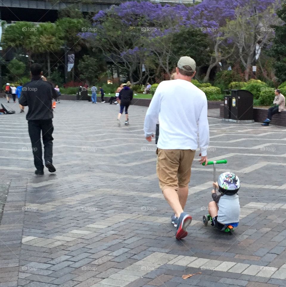 Boy pulled on scooter by Dad