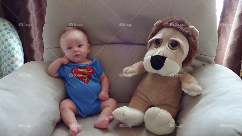 Cute baby with stuffed toy sitting on couch