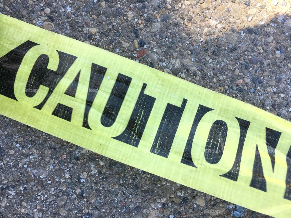 Caution tape on pavement.