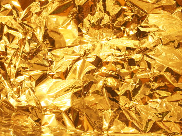 Shiny, gold-colored metal surface with cut edges.  Texture.