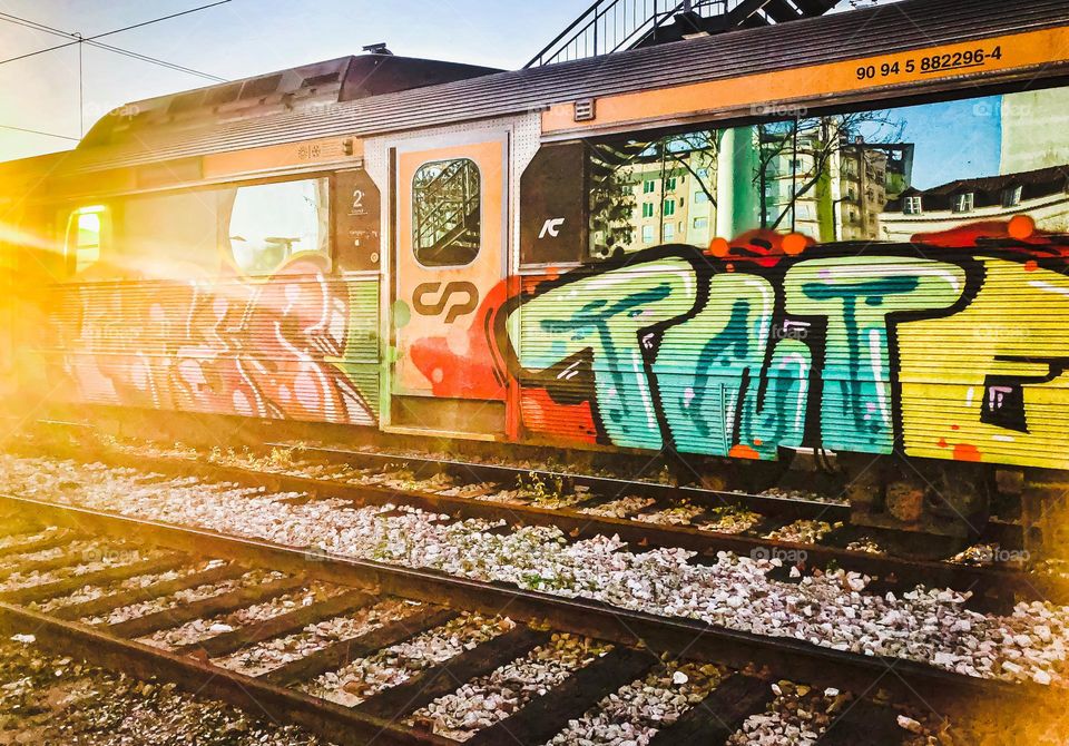 A graffitied train appears colourful in the setting sunlight, Portugal 