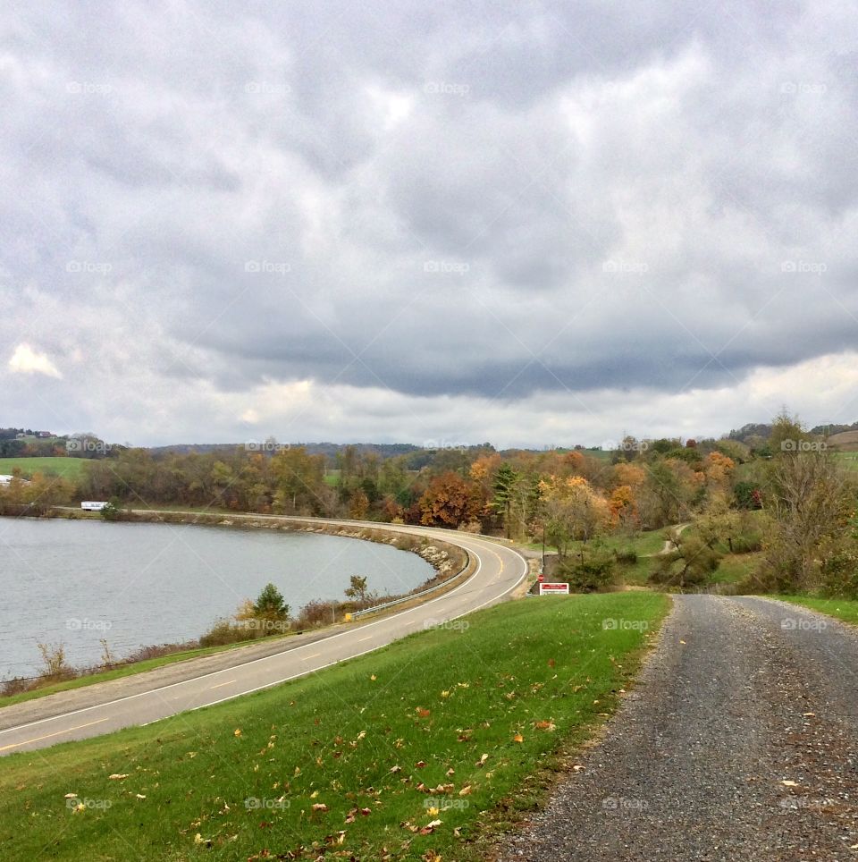 Country road beside a lake in the autumn with cloudy skies
