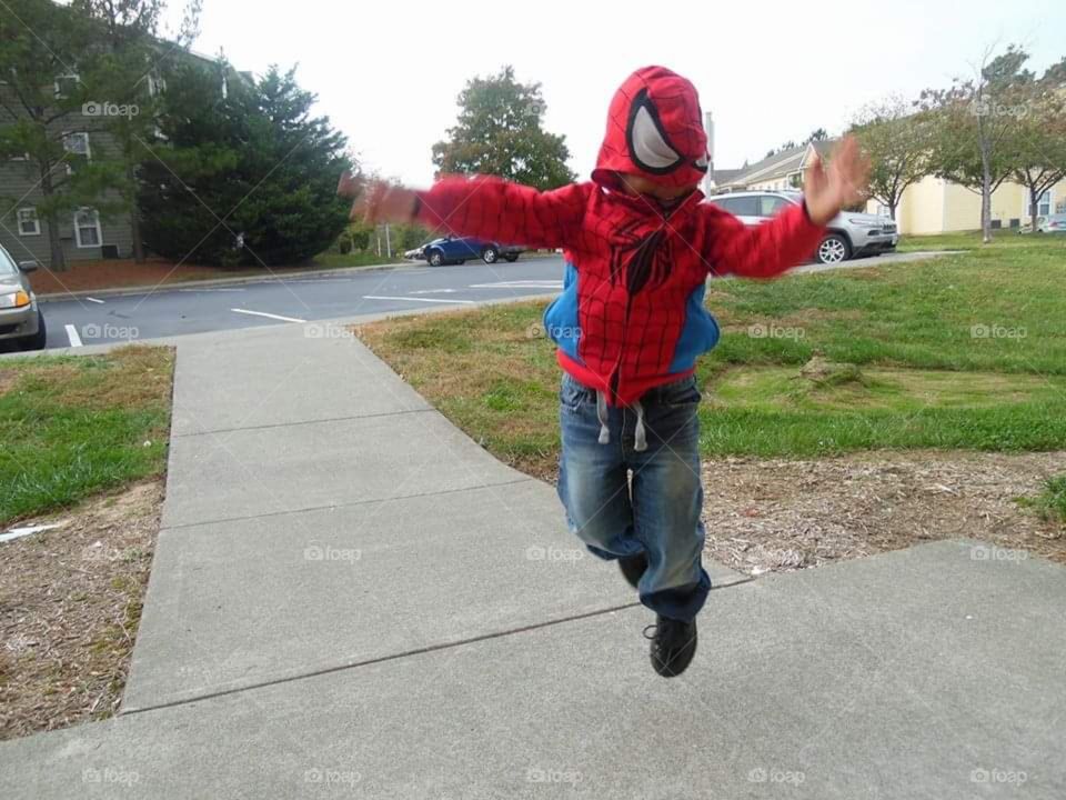 An action shot of a child posing in their favorite Marvel Universe character Spiderman.