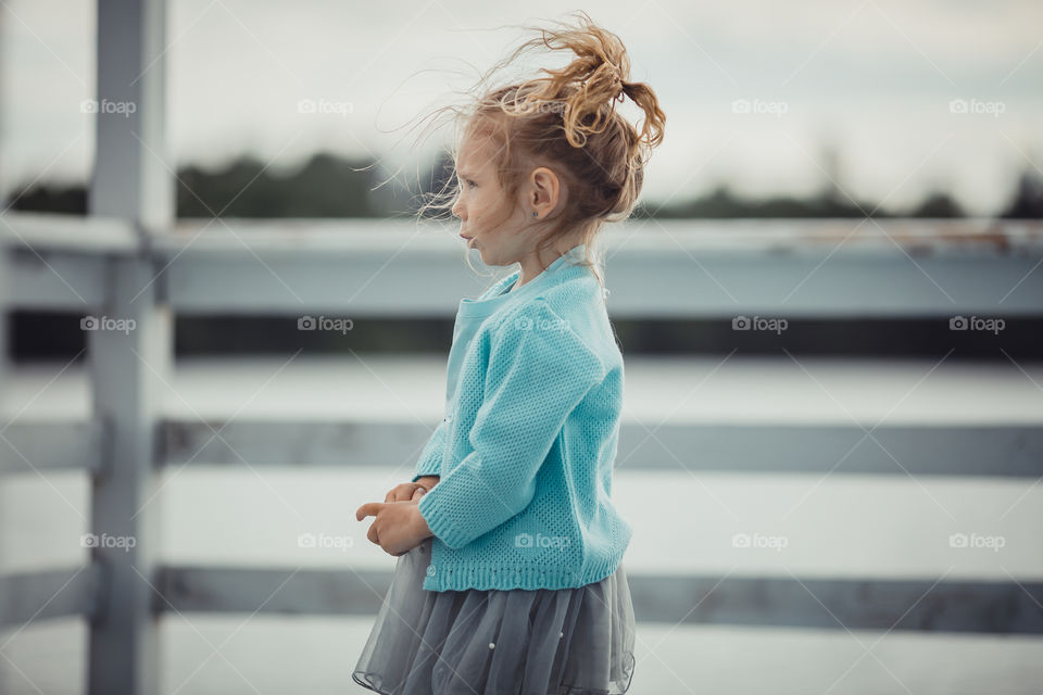 Little girl on lake coast at sunny evening. 