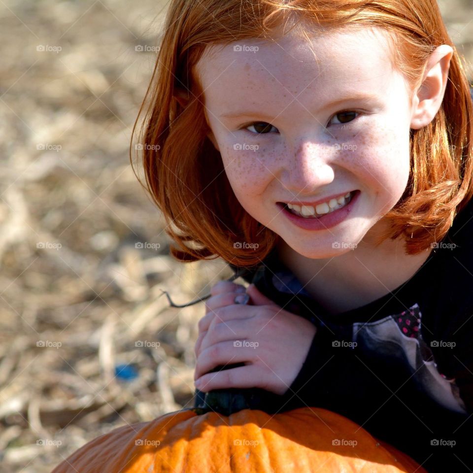 Portrait of a smiling child with a pumpkin.