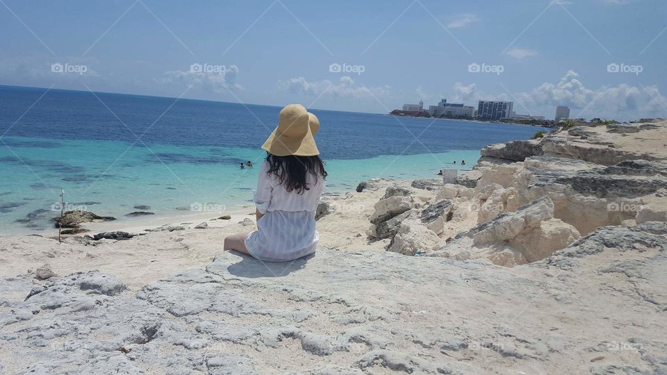 Girl sitting on white sand beach in Cancun Mexico