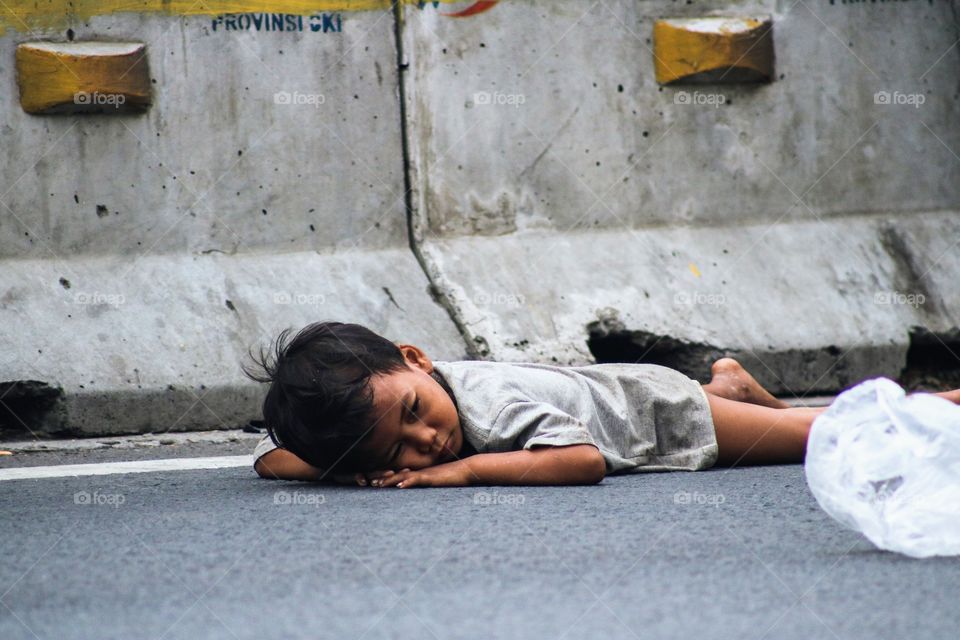 a street child lying on the street during begging at the Jakarta car free day. ( September, 15, 2019)