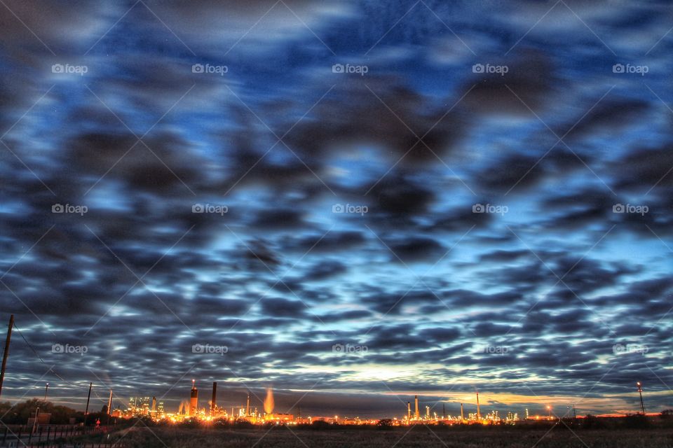 An industrial oil refinery under dark cloudy skies.