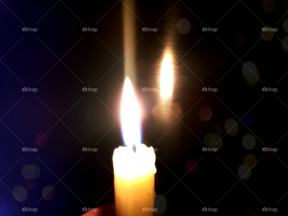 reflection of a burning candle on black glass