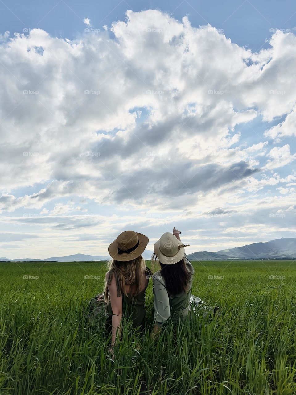 two girls sisters on a picnic in a field looking at the sky