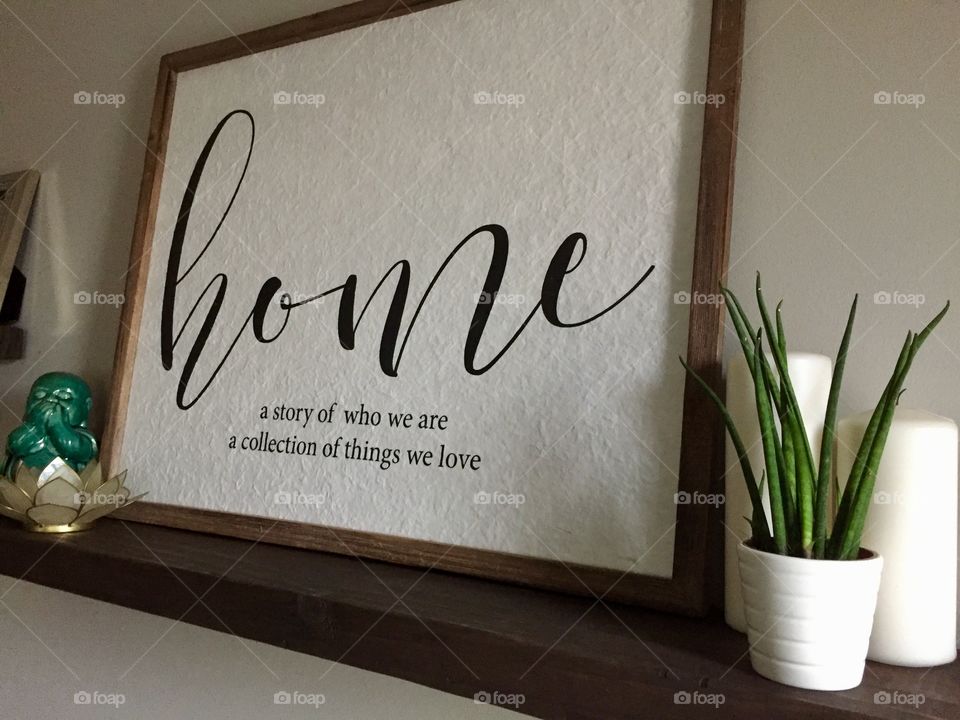 Dark wood floating shelf with framed words with small plant and candles