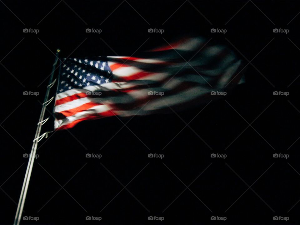 American flag emerging from the darkness with light shining on United States stars and stripes