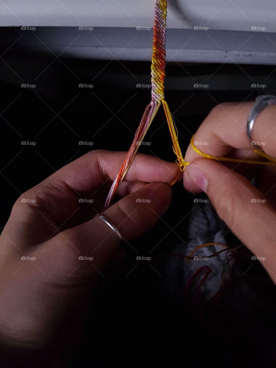 Working hands making a weaved bracelet