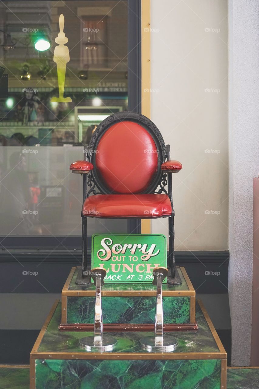 Shoe polishing service. Empty seat of shoe shine service with selective focus on wooden sign written out for lunch.