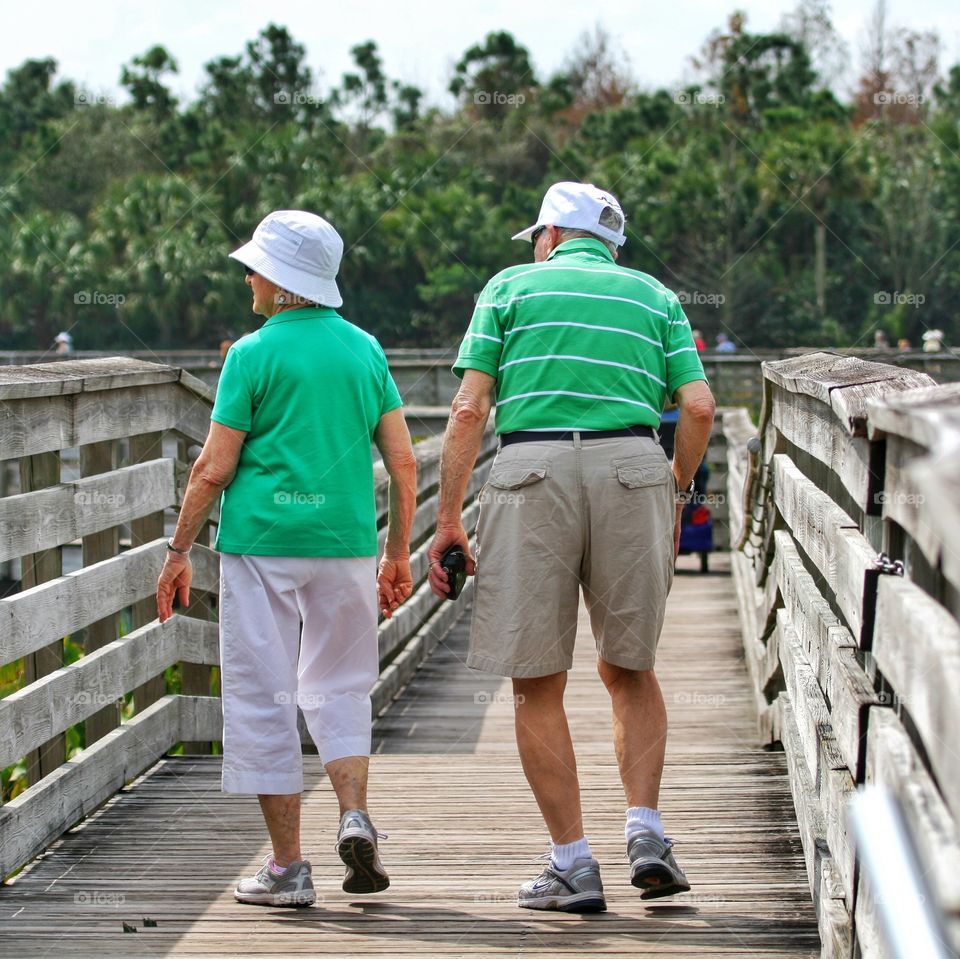 An elderly couple taking a stroll - as seen from behind.