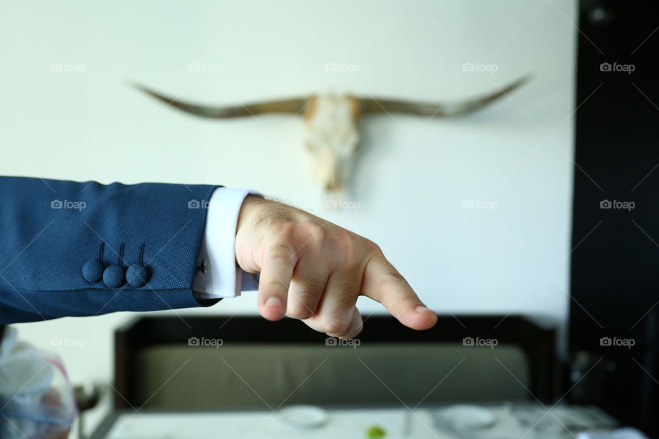 Bullhorn skull hang five. Man in blue suit and hang five with hand while bull skull hangs from the wall