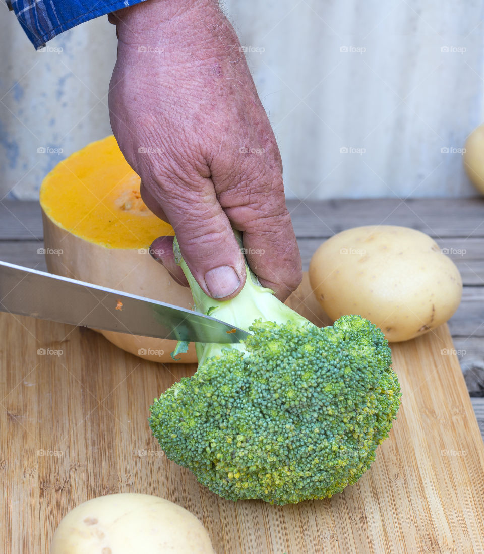 Sharp knife cutting broccoli stem.