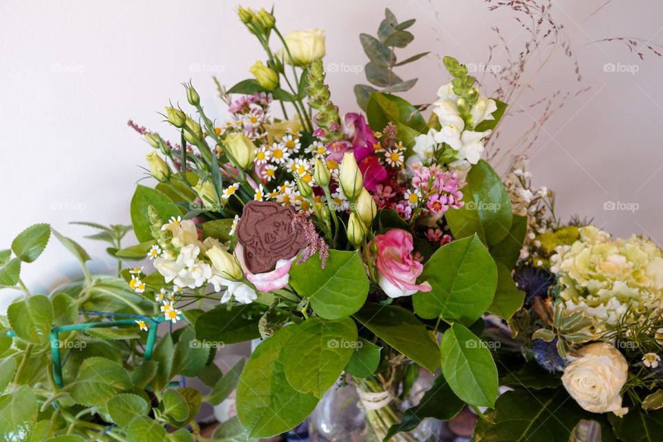 A beautiful bouquet composed of various flowers with one homemade chocolate biscuit.