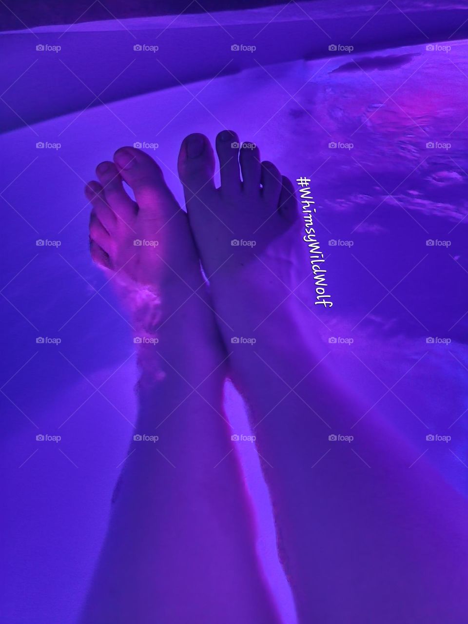 Feet relaxing in a hot tub after a long day, enjoying the soft purple glow.
