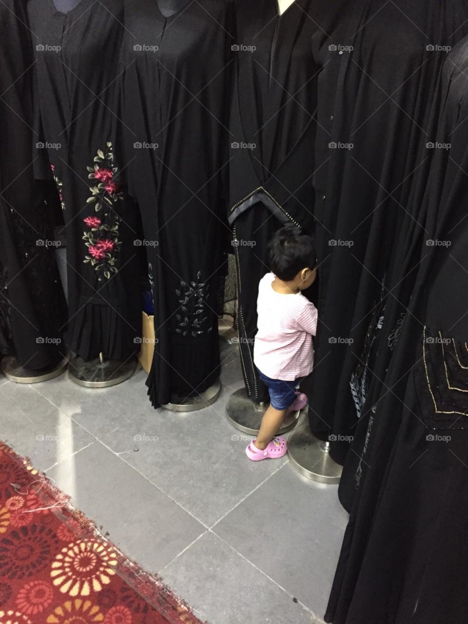 a kid playing around with abaya... looks so cute...