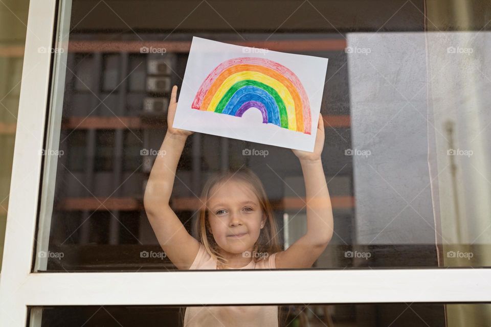 Little Caucasian girl with painted rainbow in window 