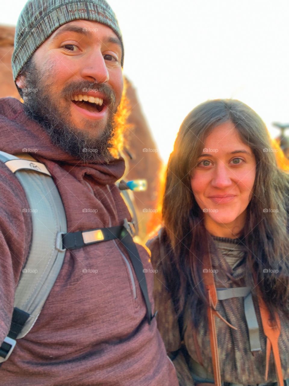 A couple of adventure seekers taking a selfie during the golden glow of sunrise in the desert. Natural colors and lighting make for a striking photograph.
