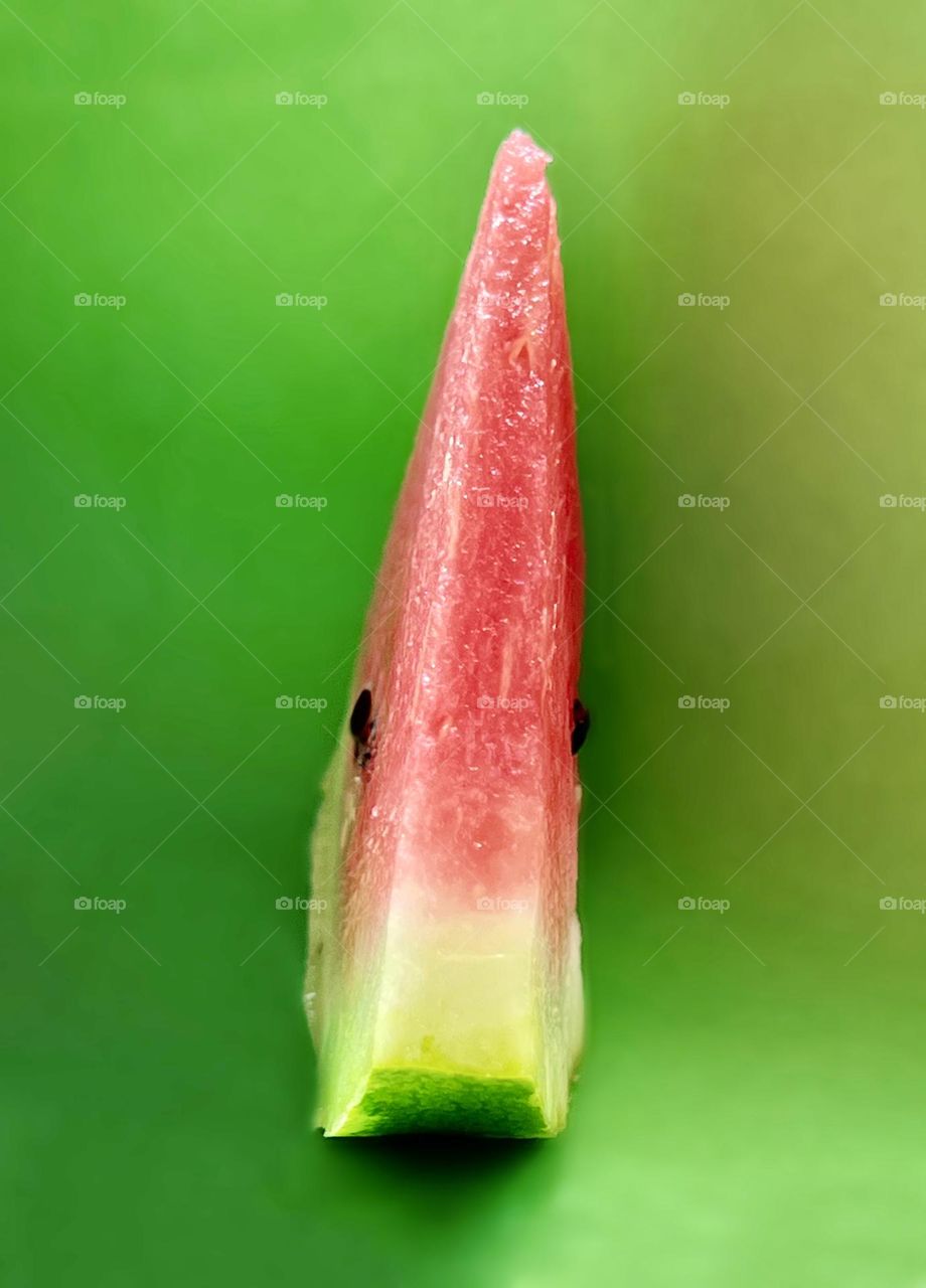 A slice of watermelon photographed against a green background