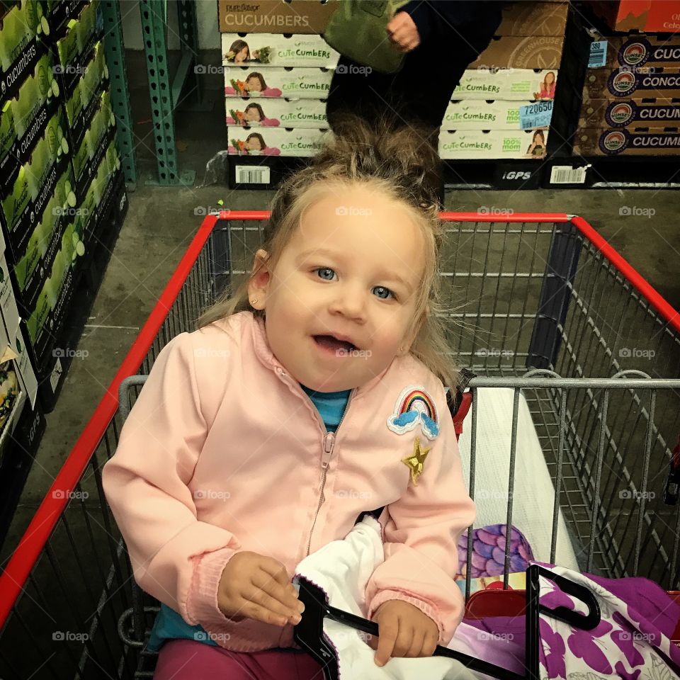 Little girl sitting in shopping cart